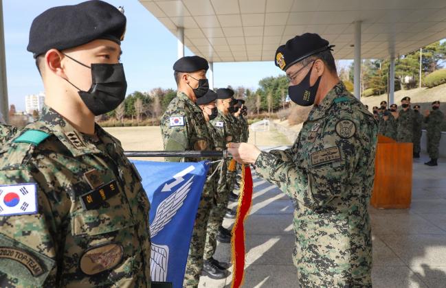 김정수(오른쪽) 육군특수전사령관이 올해 탑팀에 선발된 이동호 대위 등 독수리부대 6중대 장병들을 격려하고 부대기에 수치를 달아주고 있다.  부대 제공