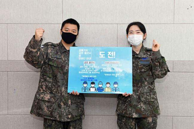 ‘새해맞이 금연 클리닉’을 신청한 공군18전투비행단의 한 장병(왼쪽)이 항공의무대대 요원과 함께 금연 클리닉 피켓을 들어 보이며 파이팅을 외치고 있다. 사진 제공=김동범 중사