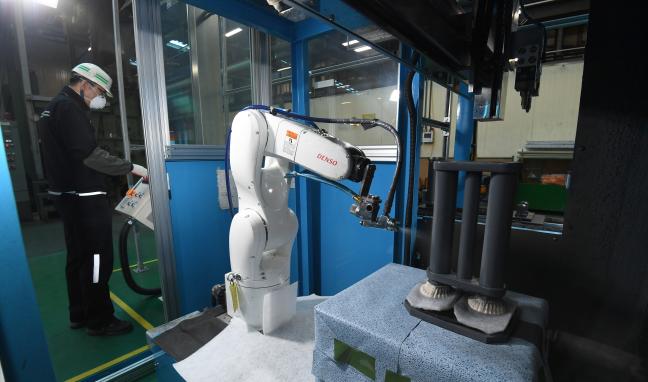 육군군수사령부 종합정비창 궤도 생산공장에서 협동로봇이 궤도 보디 접착제 도포 작업을 하는 모습.