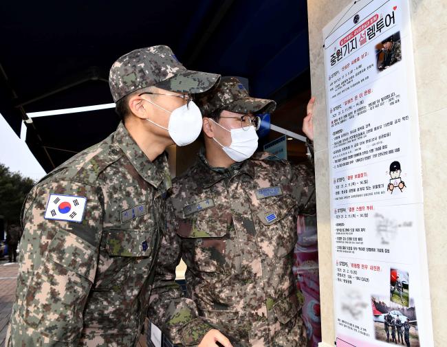 공군19전투비행단 장병들이 부대 내에 게시된 ‘중원기지 설렘투어’ 포스터를 보며 이야기를 나누고 있다.  사진 제공=지준오 중사