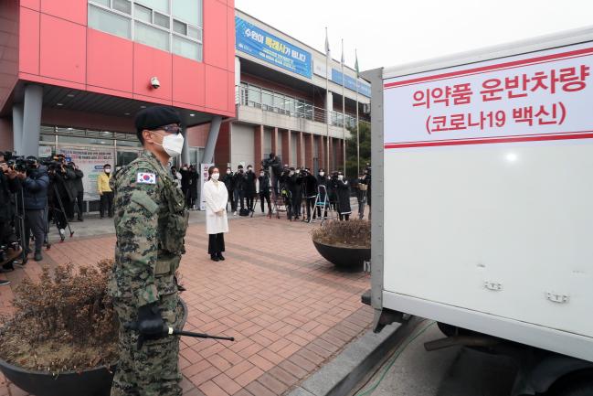 수송차량이 경기도 수원시 권선구보건소에 도착하자 보건소 직원이 육군특수전사령부 소속 특전요원의 호위 속에 대기하고 있다.