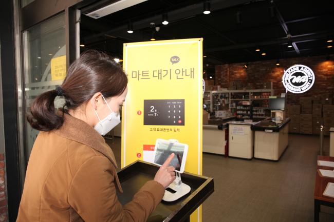 국군복지단 서울지원본부 대방마트 앞에서 한 군인가족이 마트 이용을 위해 모바일 메신저 기반 고객 대기 서비스에 자신의 휴대전화 번호를 입력하고 있다.   부대 제공