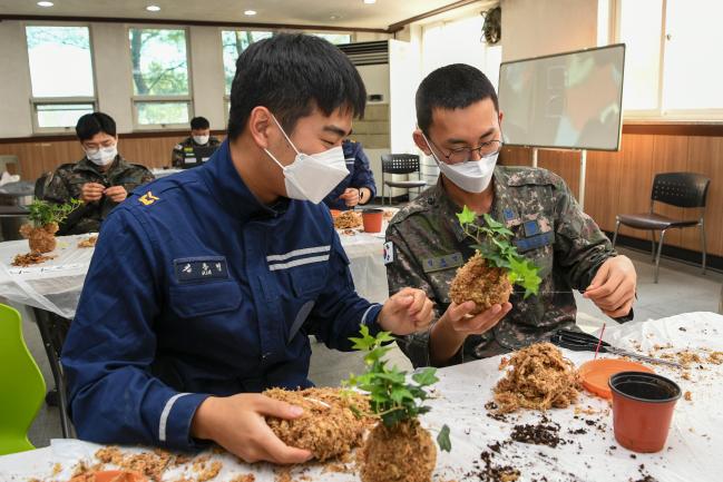 공군20전투비행단 ‘토피어리 만들기 경연대회’에서 참가자들이 이끼를 이용해 식물을 감싸며 토피어리를 만들기에 열중하고 있다.  부대 제공 