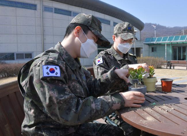 ‘나의 플랜트(Plan-T)’ 프로그램을 통해 화분을 선물 받은 공군15특수임무비행단 장병들이 반려식물 화분에 군 생활 계획과 다짐을 담은 타임캡슐을 넣고 있다.  사진 제공 = 김샛별 중사