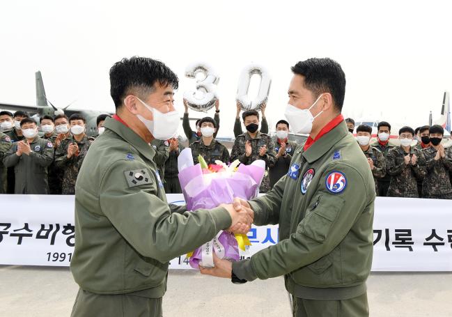공군15특수임무비행단 김현수(준장·왼쪽) 단장이 ‘256공수비행대대 30주년 무사고 비행 기록 달성 기념식’에서 김상준(중령) 256대대장에게 꽃다발을 건넨 뒤 악수하고 있다.  사진 제공=김샛별 중사 