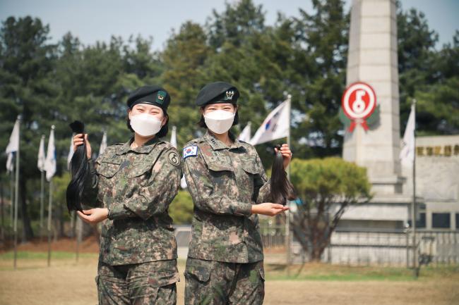 육군5사단 최송이(오른쪽) 대위와 이채린 하사가 ‘어머나 운동본부’에 기부할 자신들의 머리카락을 들고 기념사진을 찍고 있다. 
 사진 제공=최현준 상병