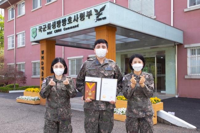 헌혈을 통해 나눔을 실천한 국군화생방방호사령부 이진협(가운데) 대위와 소아함 환자들을 위해 모발을 기부한 조선희(왼쪽) 대위, 김지영 상사가 부대 앞에서 환하게 웃고 있다.  사진 제공=최정현 일병