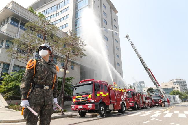 13일 합동참모본부가 진행한 화재대피훈련에서 국방부 근무지원단 소방대와 용산소방서 요원들이 소방호스를 이용해 건물 화재를 진압하고 있다.  조종원 기자