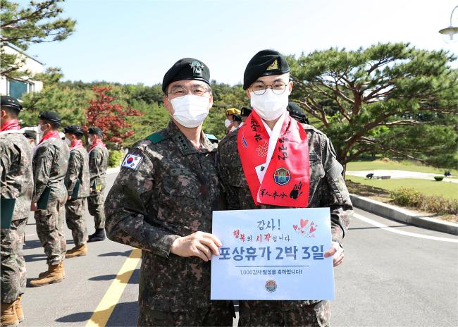 강창구(중장·왼쪽) 육군8군단장이 1000 감사를 달성한 이장한 일병에게 휴가증과 머플러를 수여한 뒤 기념사진을 찍고 있다.  부대 제공