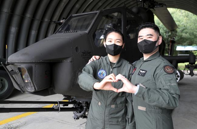‘ROTC 출신 최초의 헬기 조종사 부부’ 배준우(오른쪽)·나현선 대위가 육군1군단 11항공단 109항공대대 격납고 안에서 나 대위의 주기종인 코브라 헬기(AH-1S)를 배경으로 포즈를 취하고 있다. 