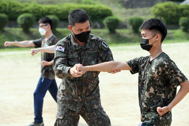 장정문 상사가 태권도 승단 심사를 앞두고 장병의 품새 자세를 교정해주고 있다. 그는 대대에서 태권도 지도자·심사관 역할을 맡고 있다.