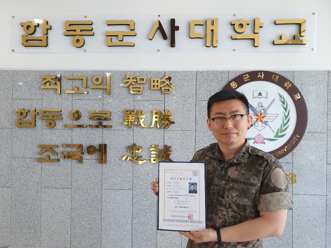 현역 육군 장교 중 최초로 정보기술(IT) 분야 최고 전문자격증인 정보관리기술사를 취득한 합동대 김민국 중령이 자격증을 들어 보이며 환하게 웃고 있다.  부대 제공