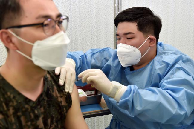 전역 전 휴가를 반납한 공군17전투비행단 항공의무대대 홍현화(오른쪽) 하사가 백신 접종을 진행하고 있다.  사진 제공=이태희 중사