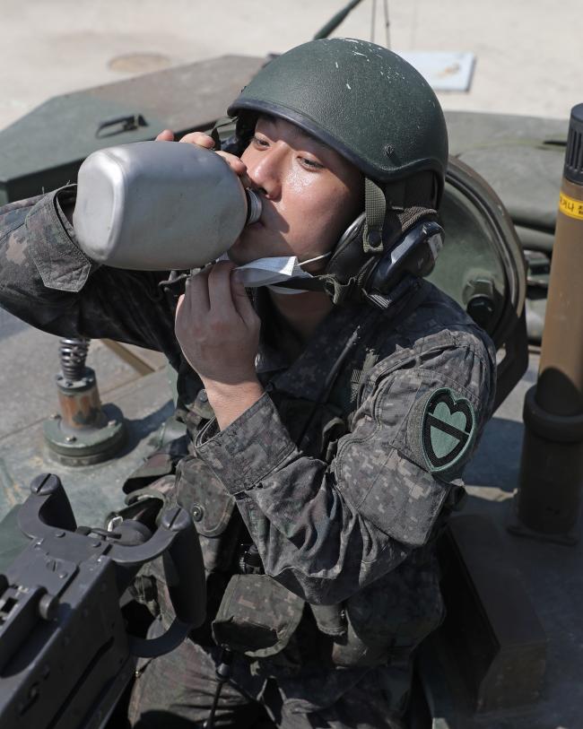 육군30기갑여단 번개대대 전차소대장 김유강 소위가 21일 전개한 K1A2 사격훈련을 마친 뒤 물을 마시고 있다. 찜통더위 속에서도 교육훈련에 매진하는 장병들은 땀으로 배출된 수분 보충을 위해 물을 자주 마셔야 한다.  이경원 기자