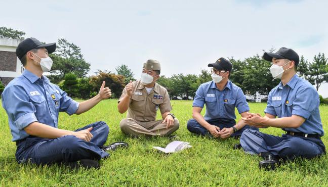 해군진기사 최천우(왼쪽 둘째) 주임상사가 수병들과 야외 잔디밭에 둘러앉아 행복한 병영생활을 위한 소통 간담회를 하고 있다.  사진 제공=전준혁 하사