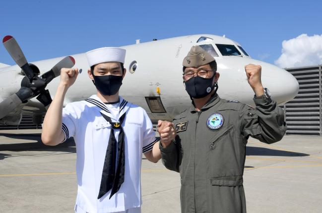 해군6항공전단에서 함께 근무하는 아버지 한동분(오른쪽) 중령과 아들 한승호 병장이 P-3 해상초계기 앞에서 파이팅을 외치고 있다.  

 사진 제공=김용헌 상사