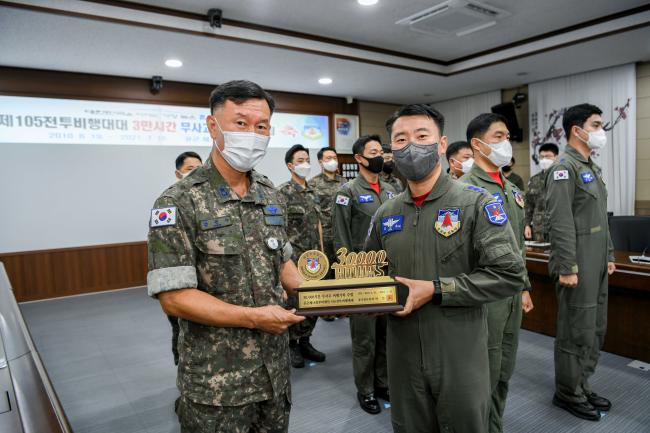 공군18전투비행단 105전투비행대대 최지훈(중령·오른쪽) 대대장이 지난 26일 비행단장으로부터 3만 시간 무사고 비행기록 기념 트로피를 받고 있다.  사진 제공=고태호 상사