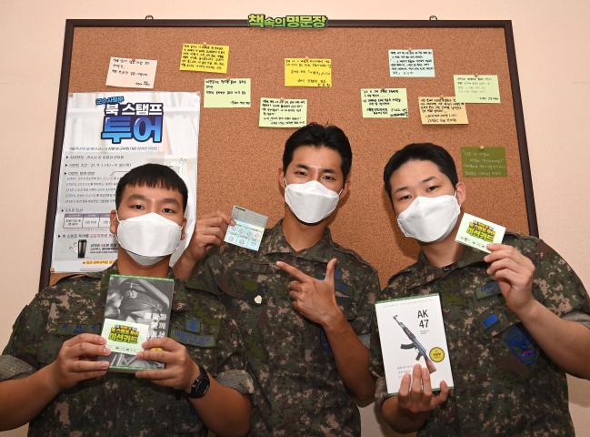 북 스탬프 투어에 참여한 공군군수사령부 장병들이 진중문고 도서와 미션 카드를 들어 보이고 있다.  부대 제공