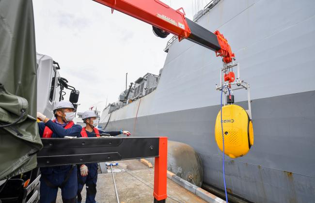 해군군수사령부 정비창 근무자들이 함정 선체 청소작업을 위해 이동용 차량 크레인으로 수중 선체 청소로봇을 함정 측면에 부착하고 있다. 
