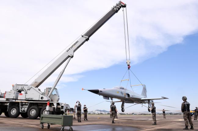 14일 공군10전투비행단 ‘활주로 폐쇄 시 처리절차 훈련’에서 기체반 장병들이 크레인을 이용해 항공기를 안전지역으로 이동시키고 있다.  부대 제공