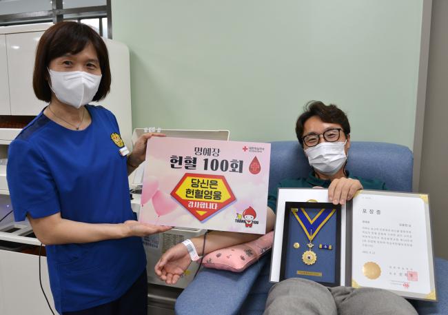 해군대학 김용현(오른쪽) 교수가 대한적십자사로부터 받은 헌혈유공장 명예장을 들고 100번째 헌혈을 하고 있다.  사진 제공=이나라 중사