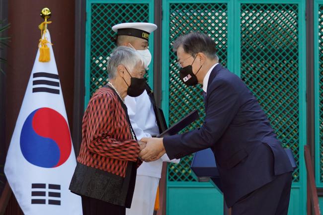 문재인 대통령이 22일(현지시각) 미국 하와이대 한국학 연구소에서 열린 독립유공자 훈장 추서식에서 독립유공자 김노디 지사 후손에게 애국장을 수여한 뒤 두 손을 꼭 잡고 있다.  연합뉴스