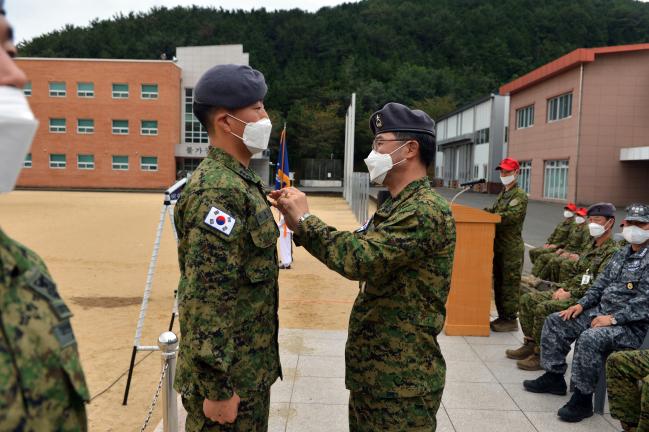 유재만(오른쪽) 해군특수전전단장이 지난달 30일 열린 제67기 1차 특수전 장교반·초급반 수료식에서 수료생에게 해군특수전 자격 휘장을 달아주고 있다.  사진 제공=이상은 상사