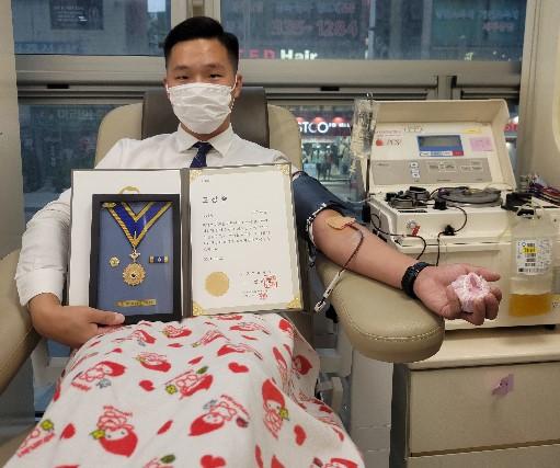 군사안보지원사령부 강재욱 중사가 헌혈하며 헌혈 유공 명예장을 들어보이고 있다.  부대 제공