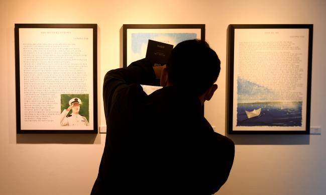 3일 서울 종로구 인사동 라 메르 갤러리에서 2021년 대한민국 해군 공모전 전시회가 열려 한 관람객이 호국 문예제 공모전 수상작들을 관람하며 휴대전화로 사진을 찍고 있다. 