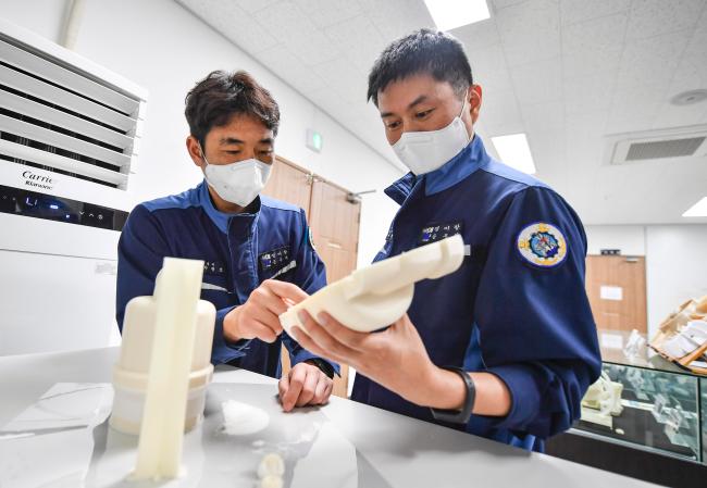 윤창한(오른쪽)·차광호 군무주무관이 3D 프린터를 활용해 시범 제작한 함정 수리부품 내부를 살피고 있다.