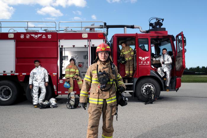 고채환 병장을 비롯한 공군18전투비행단 소방구조중대 대원들이 화재 진압과 인명 구조에 필요한 장비들을 탑재한 소방차량과 함께 포즈를 취하고 있다. 