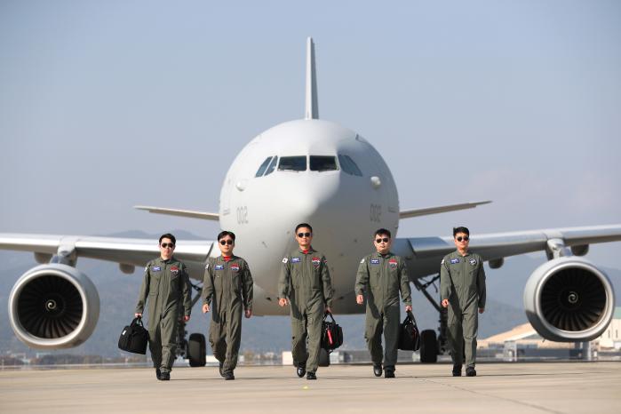 활주로 위 위풍당당한 시그너스를 배경으로 카메라 앞에 선 조주영 중령(진)과 비행대대 장병들. 