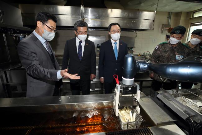 서욱(왼쪽 둘째) 국방부 장관과 문승욱(가운데) 산업통상자원부 장관이 7일 육군훈련소 28연대 식당에서 조리로봇이 튀김을 만드는 과정을 살펴보고 있다.  양동욱 기자