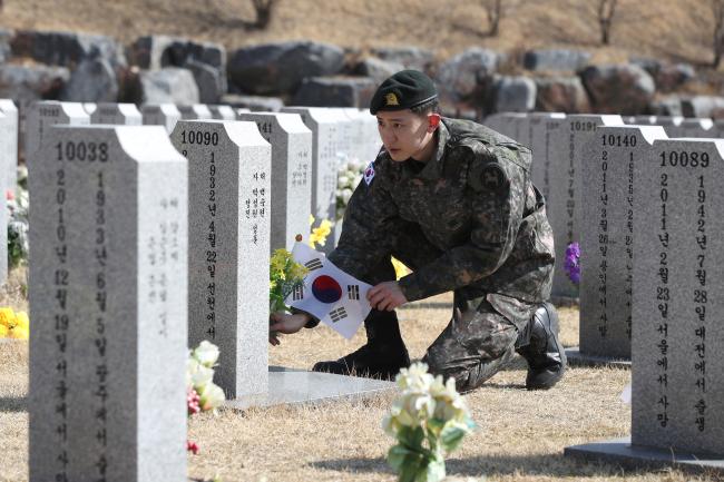 육군9보병사단 붉은황금박쥐대대 박찬열 상병이 22일 국립대전현충원에서 할아버지 박준근 옹의 묘역을 참배하고 있다. 박 상병은 촬영을 위해 잠시 마스크를 벗었다.