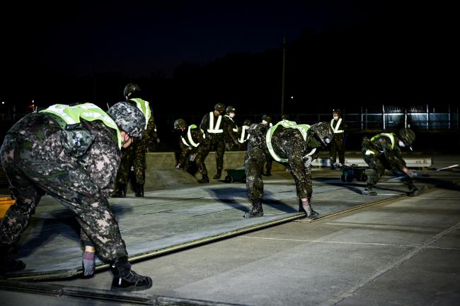 공군3훈련비행단 장병들이 지난 24일 진행된 야간 활주로 피해복구 훈련에서 알루미늄 매트를 설치하고 있다.  부대 제공