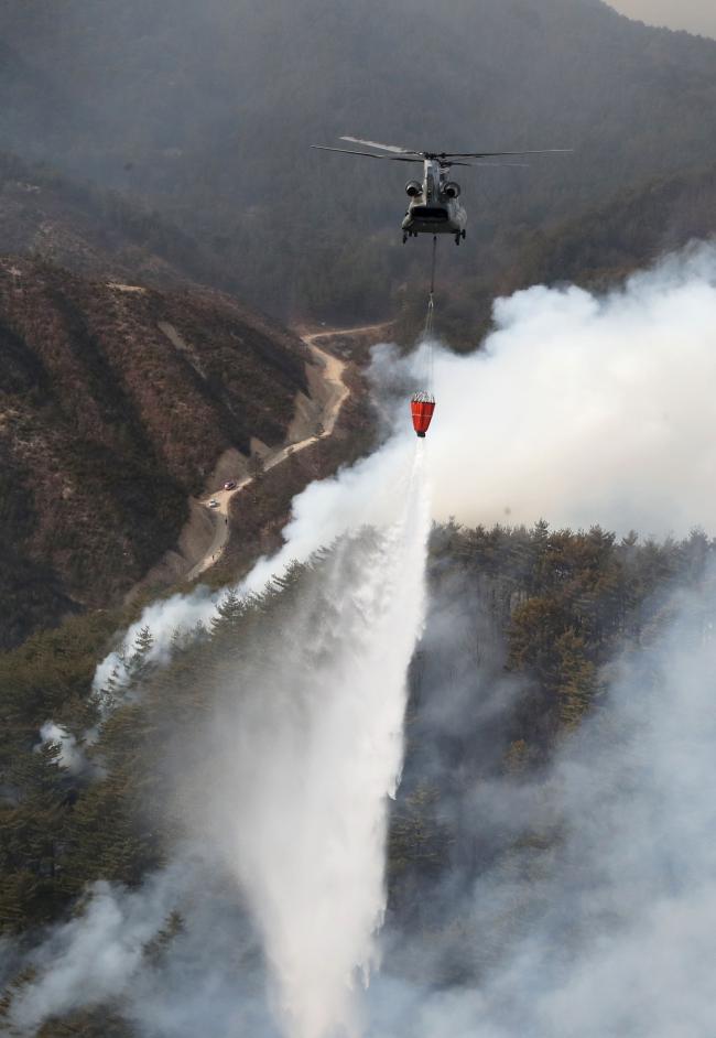 육군항공사령부 CH-47 시누크 헬기가 7일 경북 울진군 울진읍 신림리 일대 야산에서 산불 진화를 위해 물을 뿌리고 있다. 군은 이날 병력 2390여 명과 헬기 26대를 투입해 산불 진화 총력전을 펼쳤다.  양동욱 기자