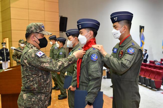 박인호(맨 왼쪽) 공군참모총장이 11일 1전투비행단에서 열린 22-1차 고등비행교육 과정 수료식에서 신임 전투 조종사에게 빨간마후라를 수여하고 있다.  사진 제공=서진철 상사