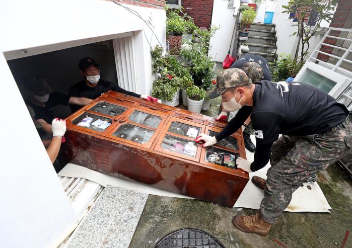 11일 오후 서울 동작구 상도동 일대 집중호우 피해 현장에서 육군52사단 기동대대 장병들이 창문을 통해 물에 젖은 가구를 밖으로 끌어내고 있다.  이경원 기자 