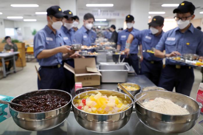 해군교육사 장병들이 밥과 반찬을 담고 있다. 앞에는 디저트로 제공된 팥빙수 재료들이 놓여 있다.