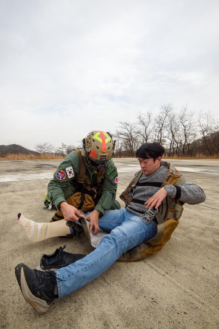 환자 역할을 맡은 기자에게 구조사가 항공구조용 조끼를 입히고 있다.