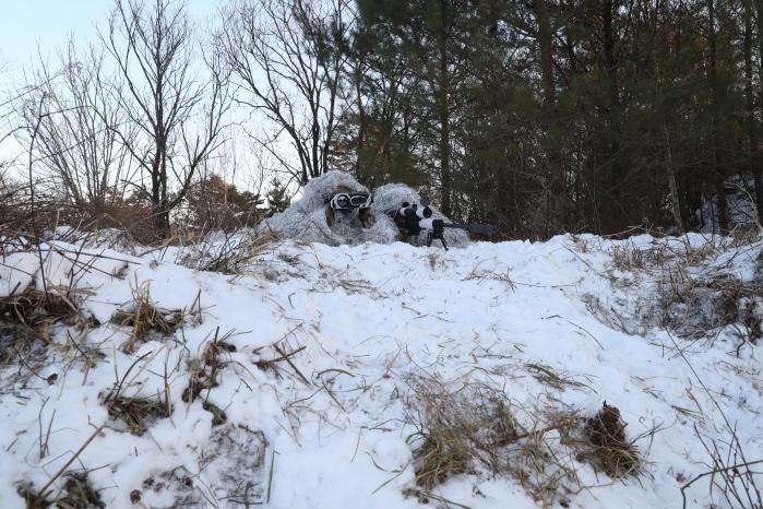 흰색 길리슈트로 위장한 저격수와 관측수가 표적을 확인하는 모습.