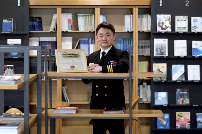유지훈 해군중령이 국방일보와 인터뷰를 마친 뒤 포즈를 취하고 있다. 왼편 액자는 그가 아시아·태평양안보연구소에서 받은 공로상.