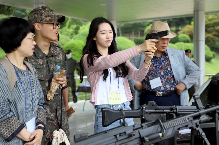 병사 가족이 전시된 권총을 들어 사격 자세를 취하고 있다.