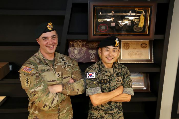 북카페 귀성쉼터에 전시된 감사패·상장·기념품 등을 배경으로 포즈를 취하는 로버트 콜라(왼쪽) 중사와 김주선 상사.