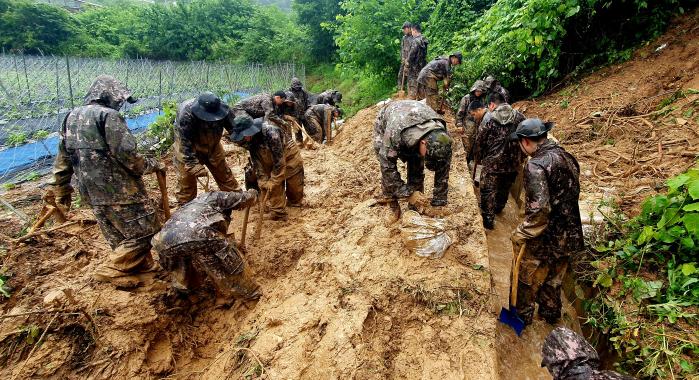 육군35보병사단 백마여단 장병들이 18일 집중호우로 붕괴 피해를 입은 전북 진안군 상전면 일대 밭 경사면에 제방을 쌓고 비탈길 배수로를 정비하고 있다. 부대 제공