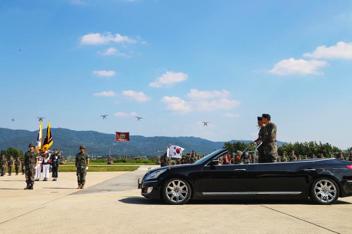 지난 1일 열린 드론작전사령부 창설식에서 김승겸(차량 앞쪽) 합참의장과 이보형 드론작전사령관이 부대를 사열하고 있다. 행사장 너머로 드론들이 비행하고 있다.