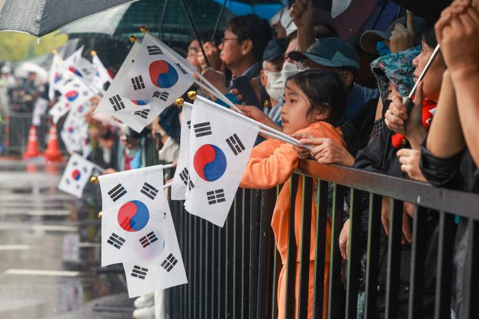 어린이를 비롯한 시민들이 시가행진하는 장병들을 향해 태극기를 흔들며 환영하고 있다.