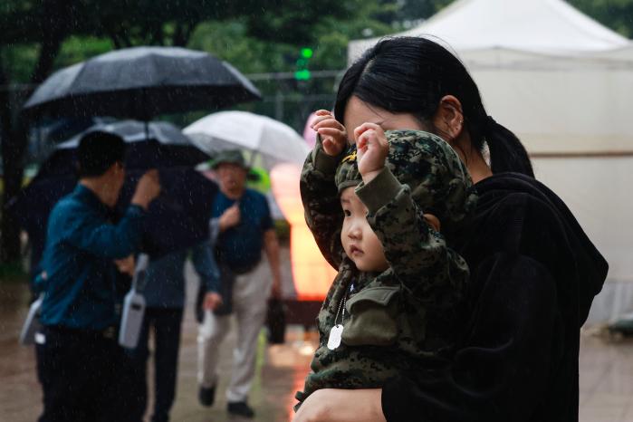 군복 디자인의 옷을 입은 어린이가 엄마와 함께 시가행진을 지켜보며 즐거운 시간을 보내고 있다.