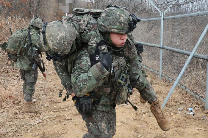 훈련 상황에서 장병이 부상자를 둘러업고 이동하고 있다.