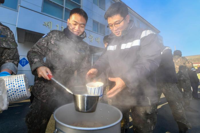 공군11전투비행단 항공기정비대대 장병이 한파에도 임무 수행에 전념하는 동료에게 어묵을 전달하고 있다.  사진 제공=권형 원사